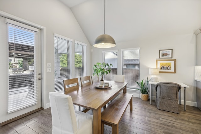 dining room with dark wood-type flooring, vaulted ceiling, and a healthy amount of sunlight