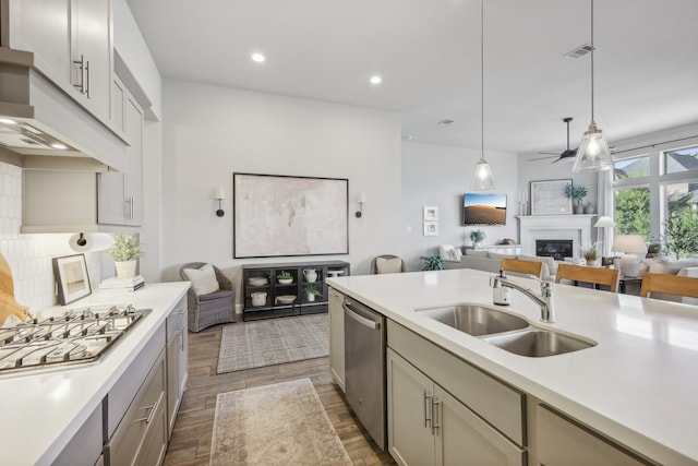 kitchen featuring gray cabinetry, appliances with stainless steel finishes, decorative light fixtures, sink, and dark wood-type flooring