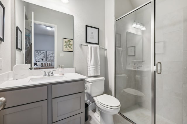 bathroom with toilet, vanity, and a shower with shower door