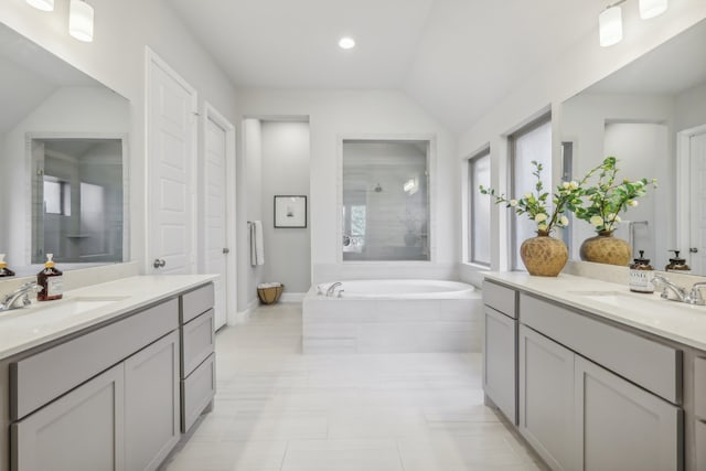 bathroom featuring vanity, vaulted ceiling, tile patterned floors, and tiled bath