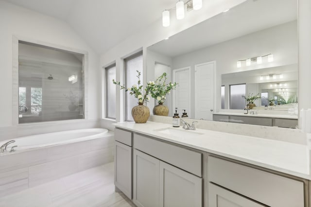 bathroom featuring shower with separate bathtub, vanity, vaulted ceiling, and a healthy amount of sunlight