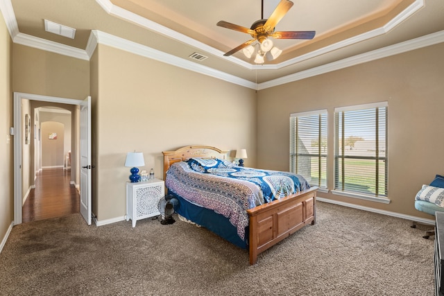 carpeted bedroom featuring a raised ceiling, ceiling fan, and crown molding