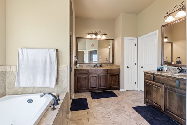 bathroom with tile patterned flooring, vanity, and tiled bath