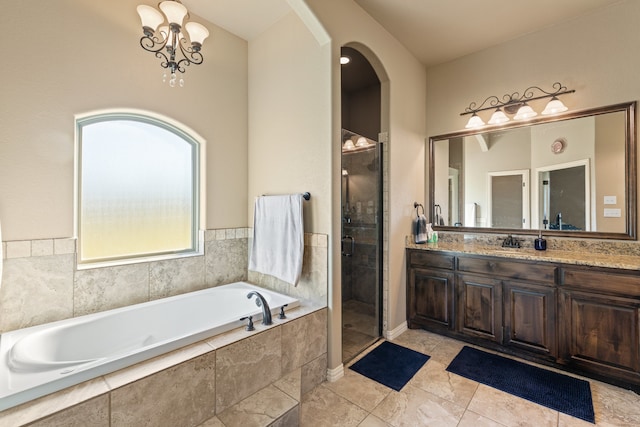 bathroom featuring plus walk in shower, vanity, a notable chandelier, and tile patterned flooring