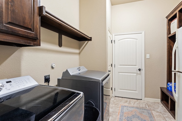 washroom featuring washer and dryer, light tile patterned flooring, and cabinets