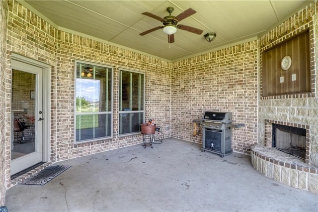 view of patio featuring an outdoor stone fireplace, ceiling fan, and area for grilling