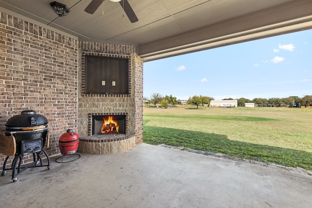 view of patio featuring an outdoor stone fireplace, ceiling fan, and grilling area