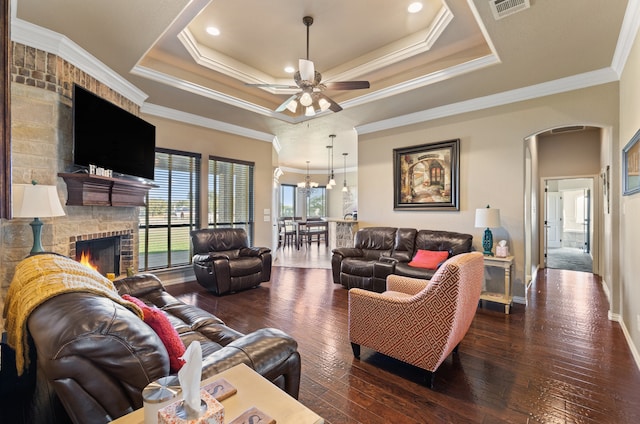 living room featuring dark hardwood / wood-style floors, a fireplace, crown molding, and a tray ceiling