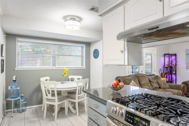 kitchen with white cabinets, dark stone countertops, and gas range