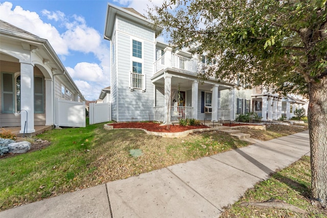 view of front of home featuring covered porch, a balcony, and a front yard