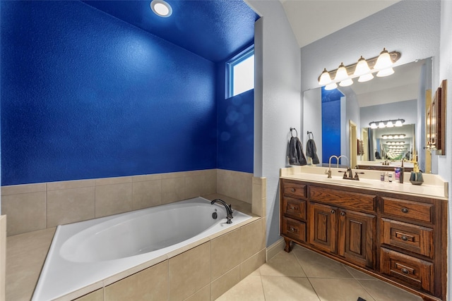 bathroom with tile patterned flooring, vanity, and tiled tub