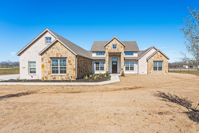 view of front facade with stone siding and fence