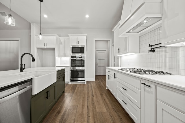 kitchen featuring stainless steel appliances, white cabinetry, light countertops, and decorative light fixtures