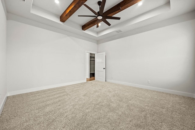 empty room featuring carpet, beam ceiling, a tray ceiling, ceiling fan, and baseboards