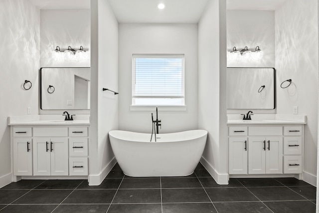 full bathroom with a sink, tile patterned flooring, two vanities, and a freestanding bath