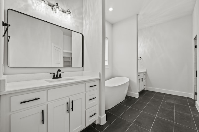 bathroom with a freestanding tub, tile patterned flooring, recessed lighting, vanity, and baseboards