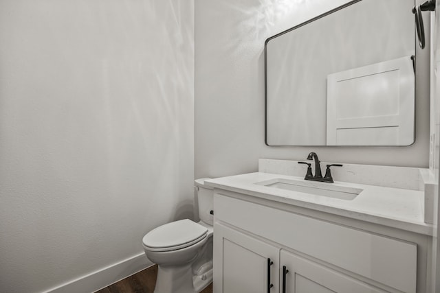 bathroom featuring baseboards, vanity, toilet, and wood finished floors