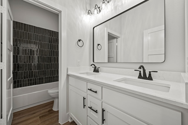 bathroom with double vanity, shower / bathing tub combination, a sink, and wood finished floors