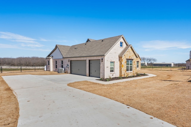 view of front of property with central air condition unit, brick siding, fence, concrete driveway, and roof with shingles