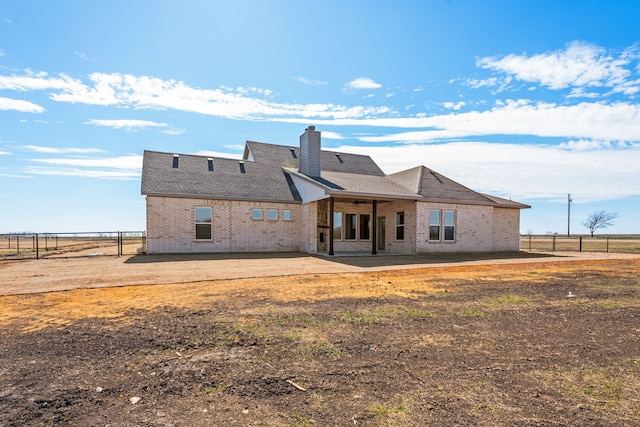 rear view of house with a patio area, a chimney, fence, and brick siding