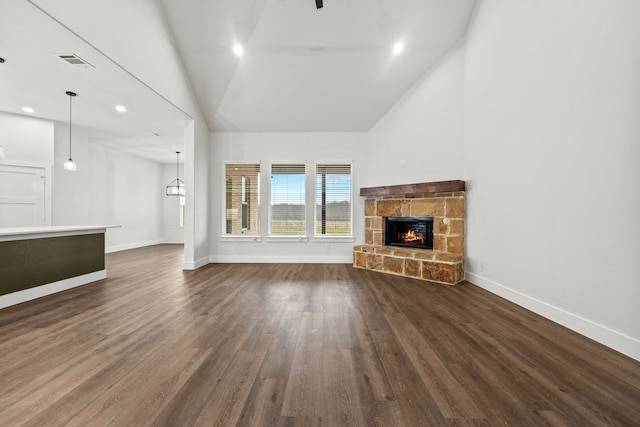 unfurnished living room featuring dark wood-style floors, recessed lighting, visible vents, a stone fireplace, and baseboards