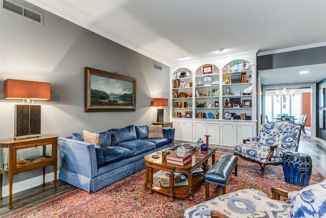 living room with built in shelves, a notable chandelier, ornamental molding, and hardwood / wood-style flooring