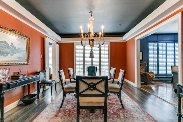 dining space with dark wood-type flooring, ornamental molding, a healthy amount of sunlight, and an inviting chandelier