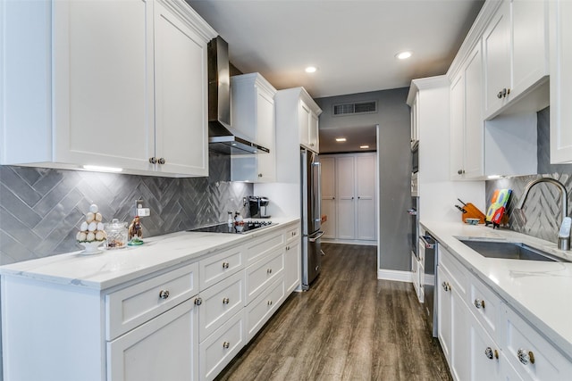 kitchen featuring appliances with stainless steel finishes, backsplash, wall chimney exhaust hood, white cabinets, and sink