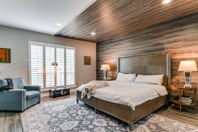 bedroom featuring wood-type flooring, wooden walls, and multiple windows