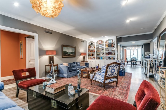 living room featuring hardwood / wood-style floors, built in features, ornamental molding, and a notable chandelier