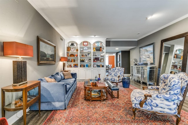 living room featuring crown molding, hardwood / wood-style floors, and built in shelves