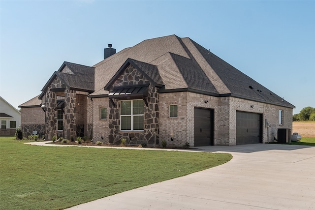 view of front of property with a garage, a front yard, and central AC