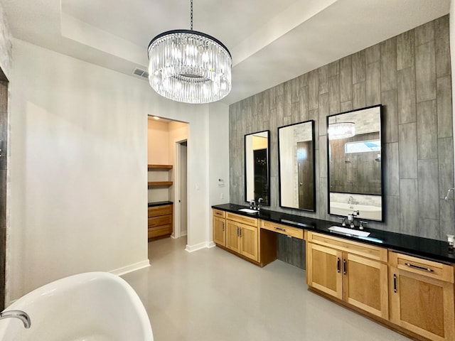 bathroom with a bathtub, vanity, concrete floors, and a notable chandelier