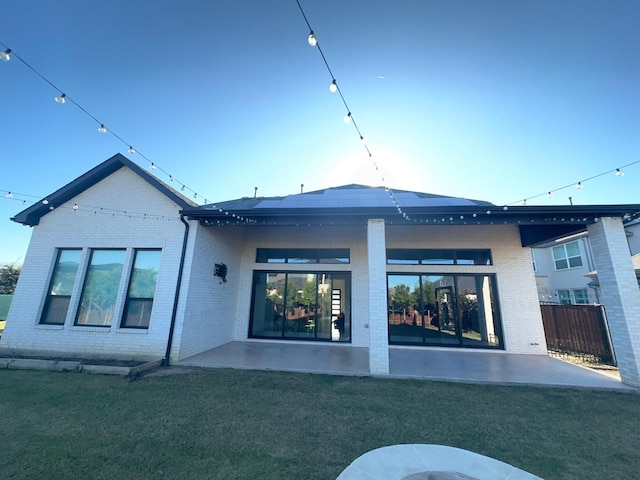 back of property with a lawn, a patio, and solar panels