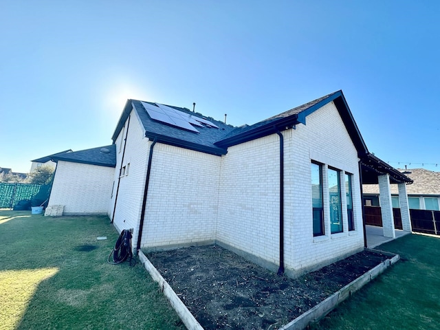 view of side of home featuring a lawn and solar panels