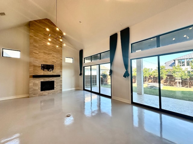 unfurnished living room with a fireplace, high vaulted ceiling, and concrete flooring