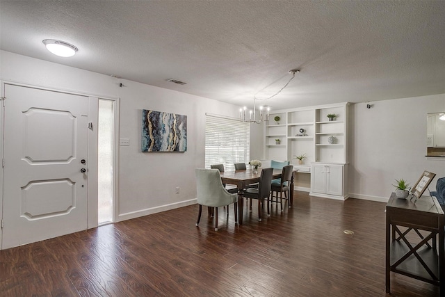 dining area featuring dark hardwood / wood-style flooring, a textured ceiling, and an inviting chandelier