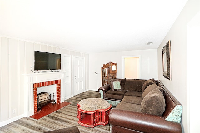 living room featuring a brick fireplace and dark wood-type flooring