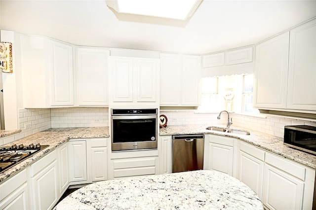 kitchen with white cabinetry, stainless steel appliances, sink, and tasteful backsplash