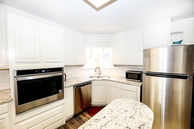 kitchen with appliances with stainless steel finishes, sink, and light stone counters