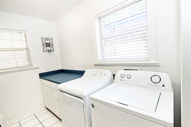 clothes washing area with washing machine and clothes dryer, light tile patterned flooring, and cabinets