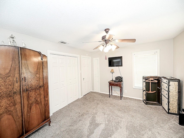 miscellaneous room featuring a textured ceiling, light carpet, and ceiling fan