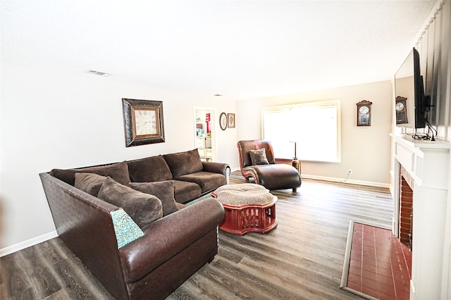 living room with a brick fireplace and hardwood / wood-style flooring