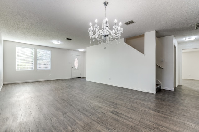 unfurnished living room featuring a textured ceiling, dark hardwood / wood-style floors, and a chandelier