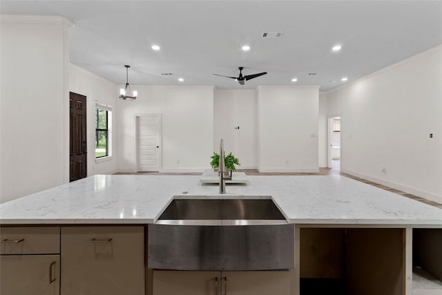 kitchen featuring light stone counters, sink, a kitchen island with sink, and hanging light fixtures