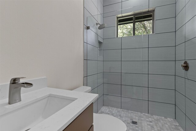 bathroom with vanity, toilet, and tiled shower