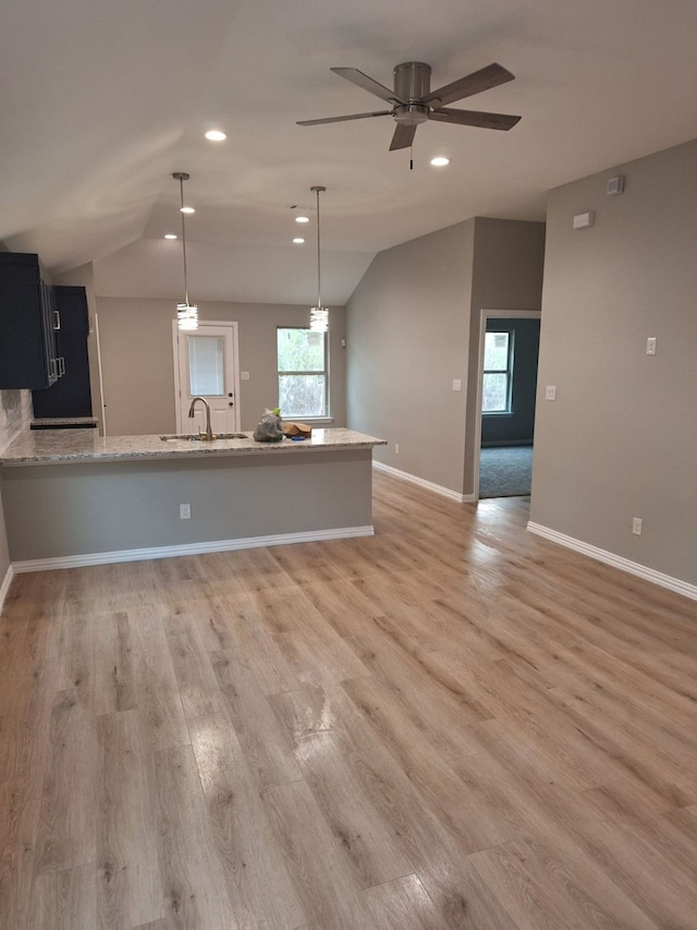 kitchen with kitchen peninsula, decorative light fixtures, lofted ceiling, and a healthy amount of sunlight