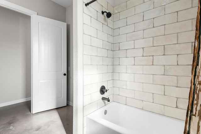 bathroom featuring concrete flooring and tiled shower / bath