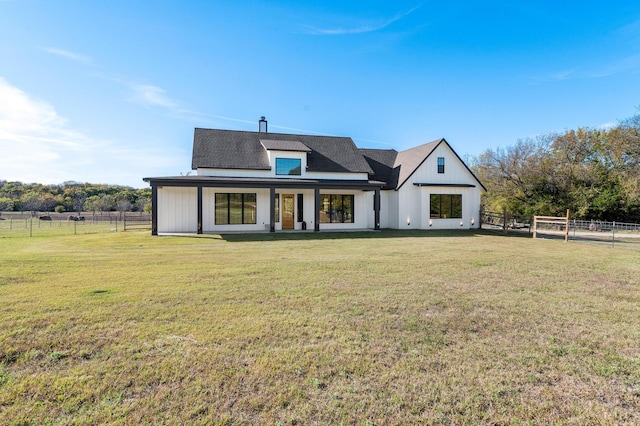 back of house with a rural view and a yard