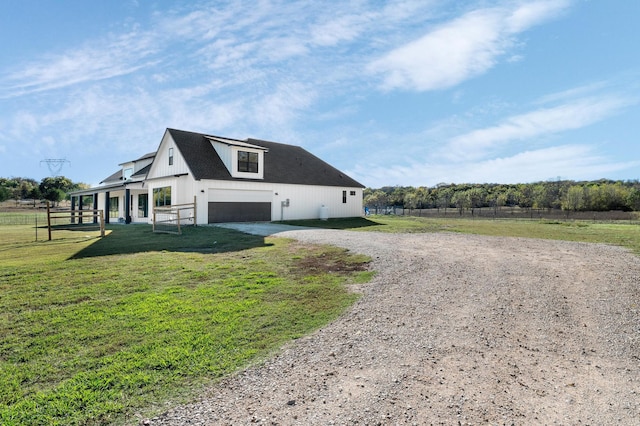 view of side of home with a lawn, a garage, and covered porch